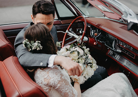 just married bride and groom in a car with red interiors